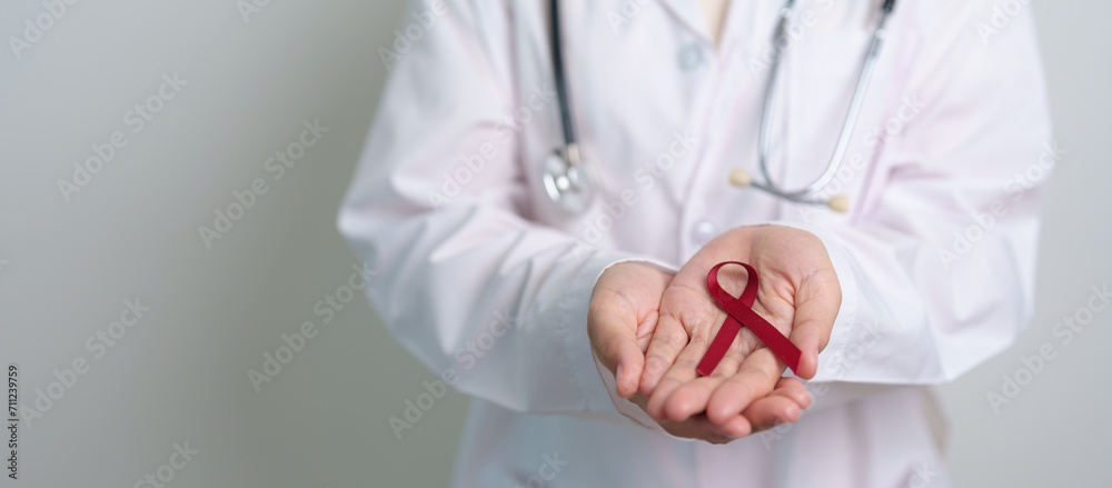 Doctor with Burgundy Red Ribbon for March multiple myeloma Cancer and December World Aids Day Awareness month. Healthcare and world cancer day concept Doctor with Burgundy Red Ribbon for March multiple myeloma Cancer and December World Aids Day Awareness month. Healthcare and world cancer day concept