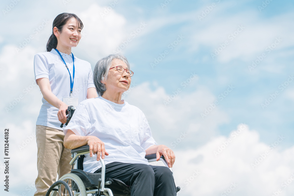 青空と介護福祉士・介護士と高齢者・シニア女性・おばあちゃん
