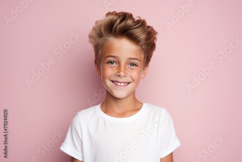 Portrait of a cute little boy with blond hair on a pink background