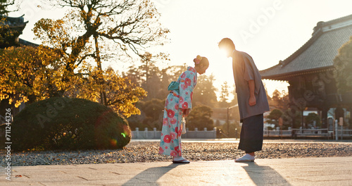 Japanese people at temple, bow and traditional clothes with hello, nature and sunshine with respect and culture. Couple outdoor, greeting with modesty and tradition, polite and kind for religion photo