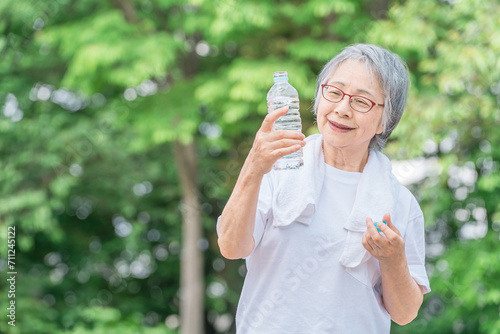 公園で水を飲みながら運動・ウォーキング・歩く高齢者女性
 photo