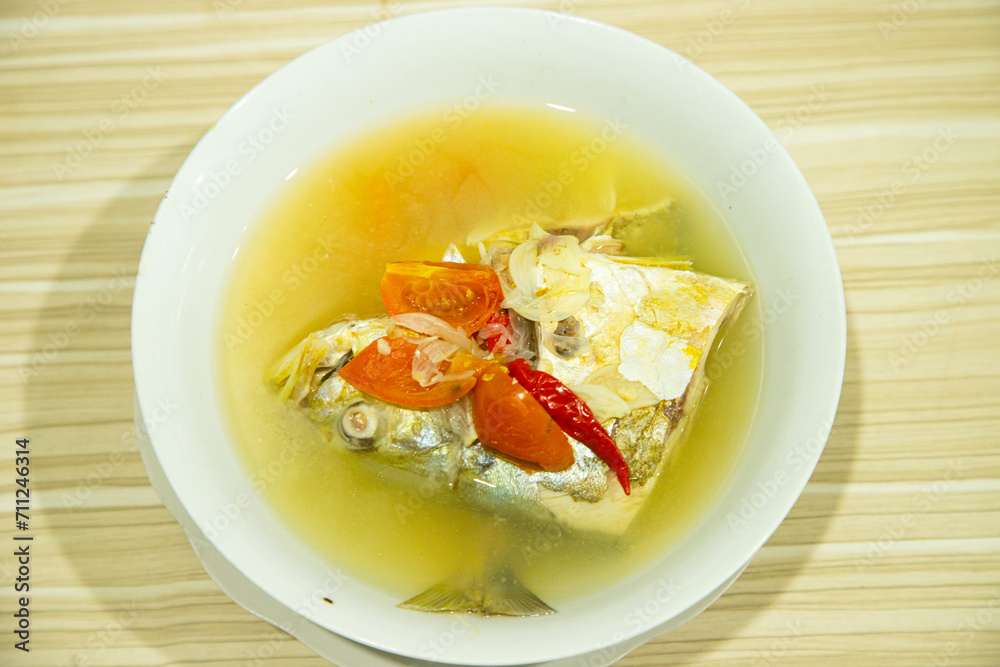 Fresh and delicious cooked fish in yellow sauce served in a white bowl Fresh and delicious cooked fish in yellow sauce served in a white bowl