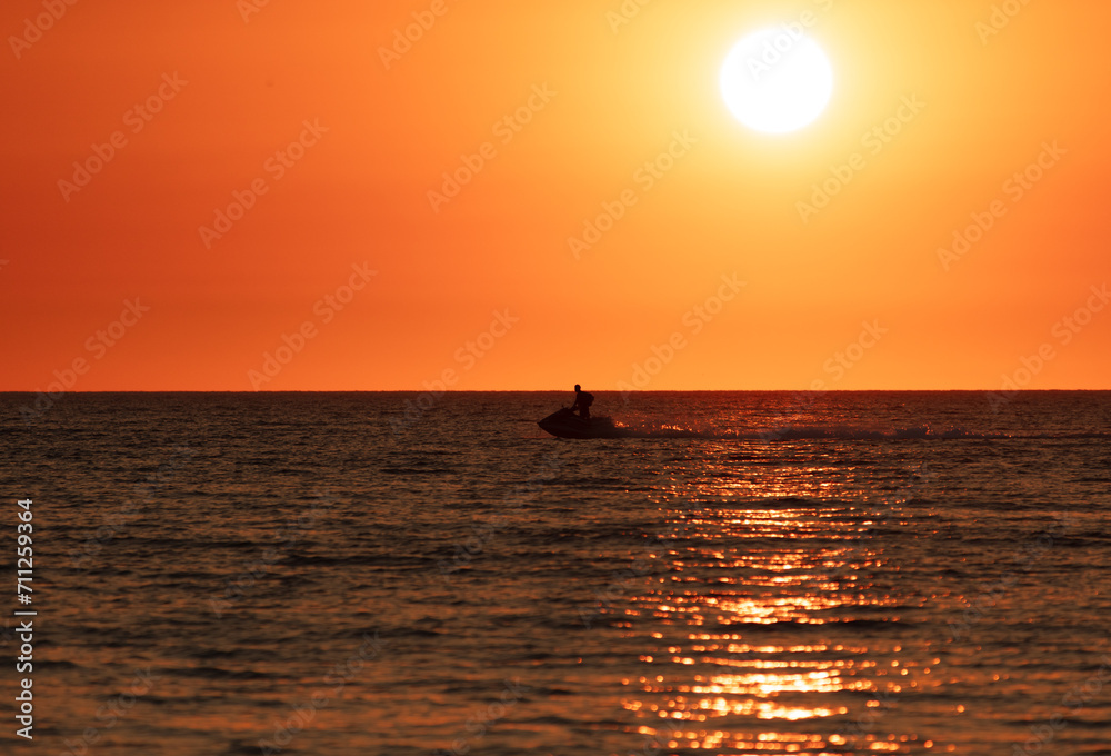 A man on a water scooter rides along the sea. sunset A man on a water scooter rides along the sea. sunset