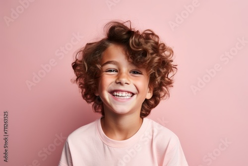 Portrait of a smiling little girl with curly hair against pink background