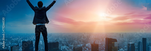 businessman on top of skyscraper celebrating success with hands in the air photo