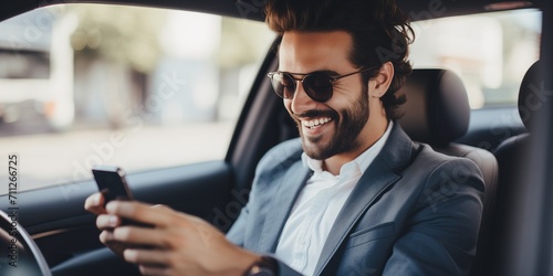 Happy man using smart phone sitting in a car © xartproduction