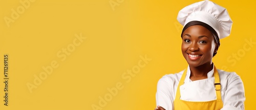 Happy black woman chef in yellow apron and hat on yellow background. Food and cooking concept. Horizontal banner with space for text.