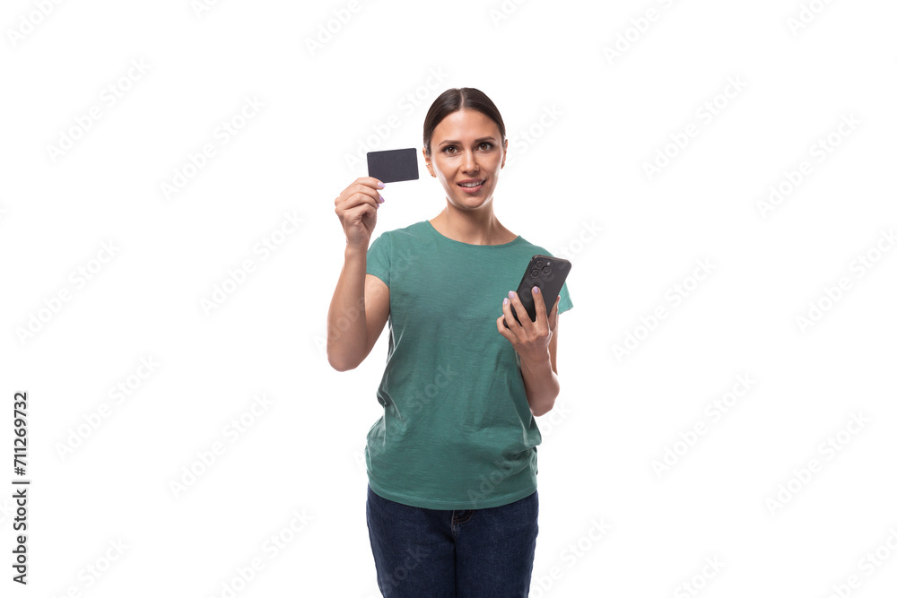 a young woman with black hair and a slim figure dressed in a green t-shirt advertises a discount card with a mock-up holding a phone in her hand a young woman with black hair and a slim figure dressed in a green t-shirt advertises a discount card with a mock-up holding a phone in her hand