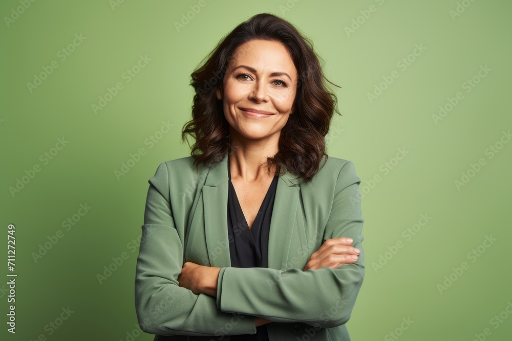 Portrait of mature business woman with crossed arms against green background. Portrait of mature business woman with crossed arms against green background.