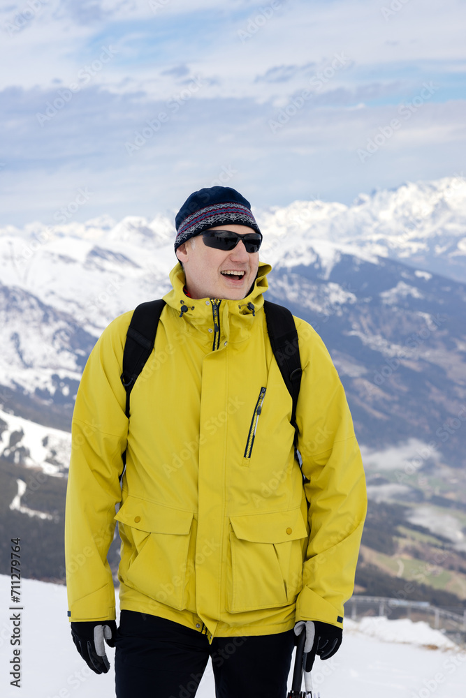 Athlete in yellow jacket and sunglasses, alpine snow-capped peaks