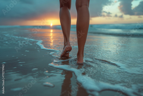 legs of a woman walking along the beach in the surf