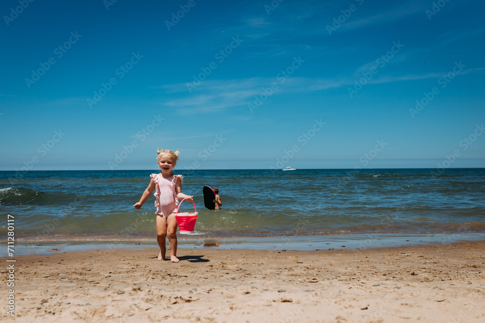 Young child with sand bucket on beach of Lake Michigan Young child with sand bucket on beach of Lake Michigan