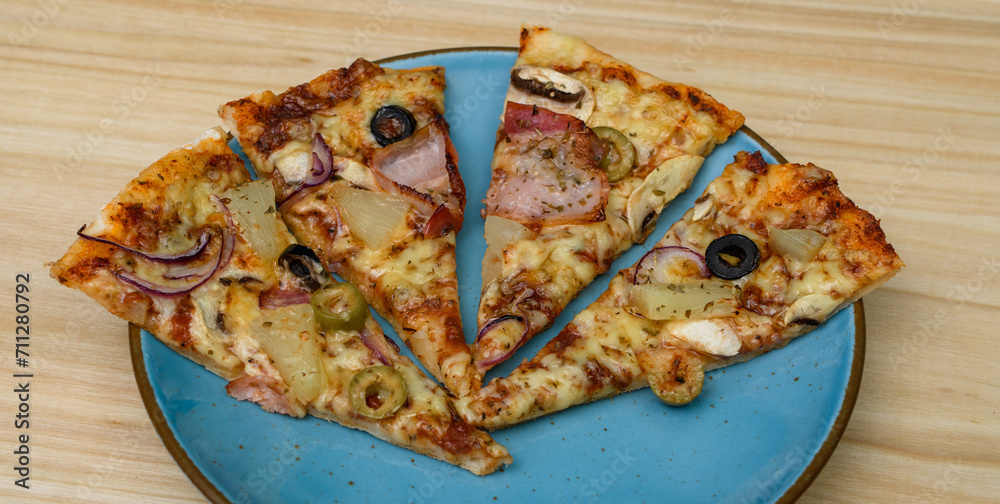 Φωτογραφία Pizza domowa pokrojona na kawałki leży na niebieskim talerzu na stole