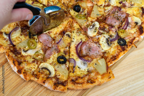 Gorąca pizza krojona nożem do pizzy na trójkątne kawałki, z bliska