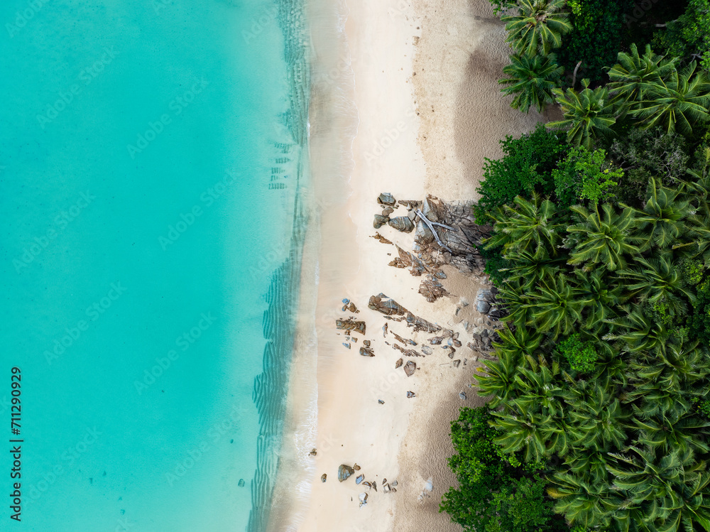 View from above, stunning aerial view of Banana beach, a beautiful white sand beach surrounded by palm trees and bathed by a turquoise water. Phuket, Thailand.