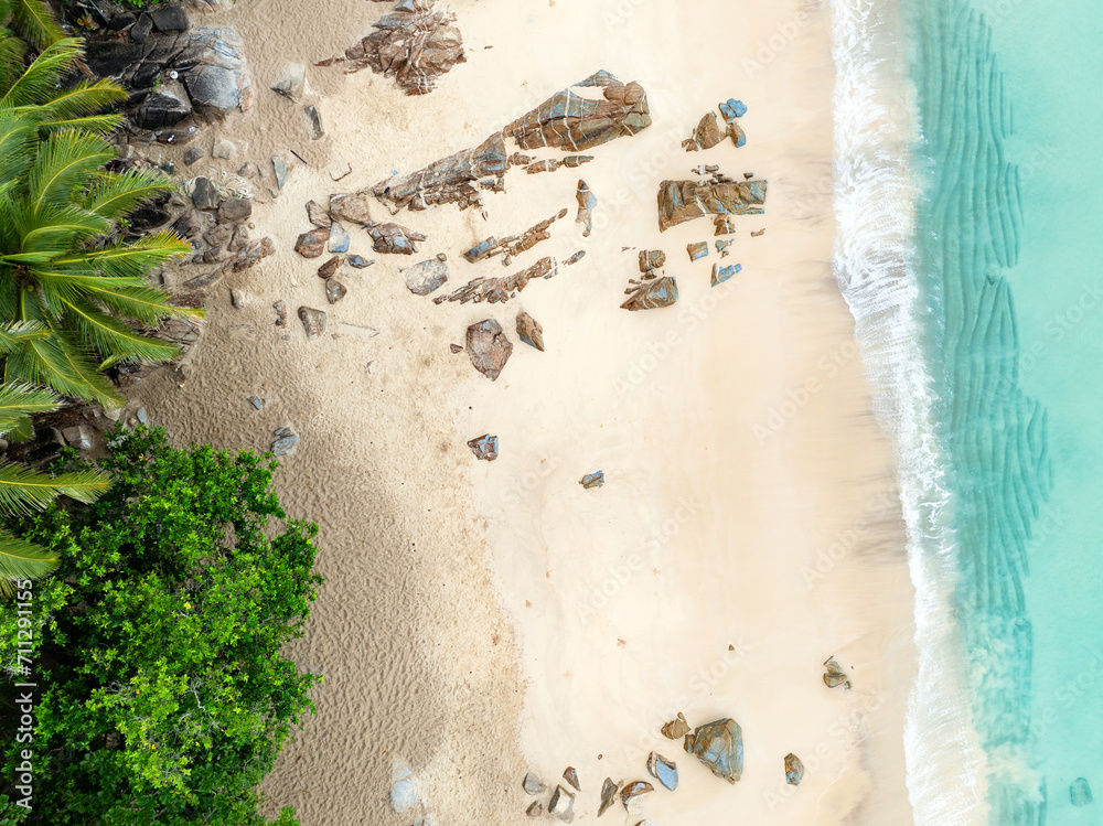 View from above, stunning aerial view of Banana beach, a beautiful white sand beach surrounded by palm trees and bathed by a turquoise water. Phuket, Thailand.