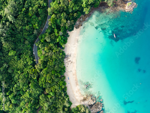 View from above, stunning aerial view of Banana beach, a beautiful white sand beach surrounded by palm trees and bathed by a turquoise water. Phuket, Thailand.