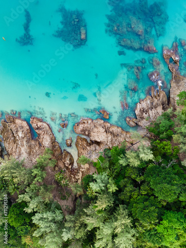 Obraz na płótnie View from above, stunning aerial view of a rocky coastline surrounded by palm trees and bathed by a turquoise water. Phuket, Thailand. w salonie