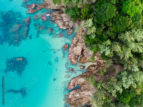Obraz na płótnie View from above, stunning aerial view of a rocky coastline surrounded by palm trees and bathed by a turquoise water. Phuket, Thailand. w salonie