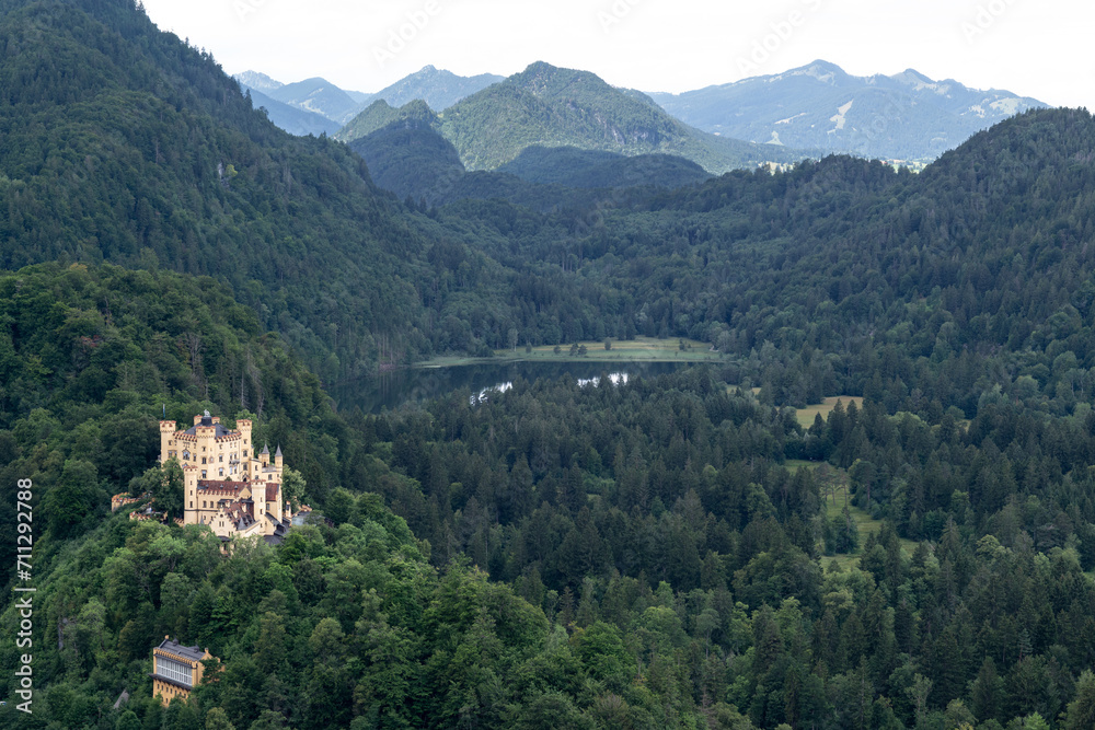 View of Hohenschwangau castle located at the top of a hill,  surrounding of a forest, a lake and mountains in Germany.