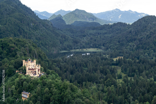 View of Hohenschwangau castle located at the top of a hill, surrounding of a forest, a lake and mountains in Germany.