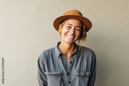 Portrait of a smiling young woman wearing hat and shirt against grey background