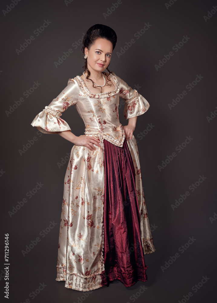 Beautiful woman in rococo style medieval dress standing against dark background Beautiful woman in rococo style medieval dress standing against dark background