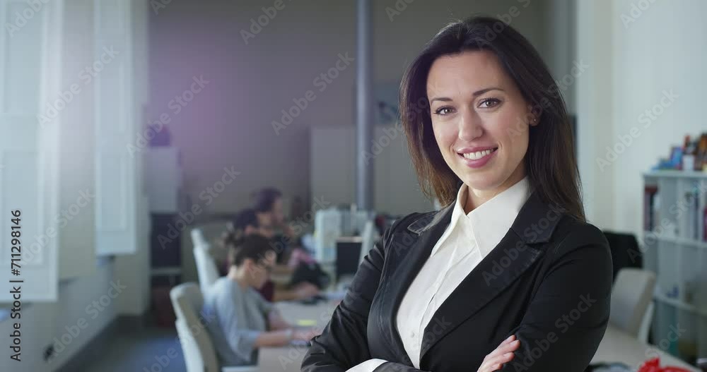 Close-up of the Beautiful Businesswoman in Office, Looking at Camera and Smiling. Confident Female Business Owner in Formal Clothes Feeling Empowered and Posing In the Background Colleagues Working Close-up of the Beautiful Businesswoman in Office, Looking at Camera and Smiling. Confident Female Business Owner in Formal Clothes Feeling Empowered and Posing In the Background Colleagues Working