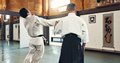 Aikido, master and fight with a sensei in martial arts with student of self defence, discipline and training. Demonstration, class or Japanese man with black belt in fighting with education of skill photo