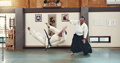 Aikido, sensei and fight with a master in martial arts with student in self defence, discipline and training. Demonstration, class or Japanese man with black belt in fighting with education of skill photo