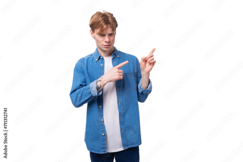 a young red-haired guy in a blue denim shirt actively gesticulates. advertising concept a young red-haired guy in a blue denim shirt actively gesticulates. advertising concept