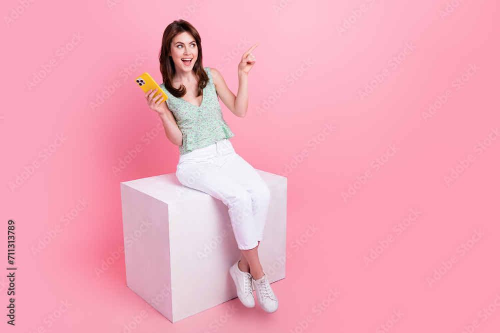 Photo of astonished lovely girl wear trendy clothes presenting novelty looking empty space banner isolated on pink color background Photo of astonished lovely girl wear trendy clothes presenting novelty looking empty space banner isolated on pink color background