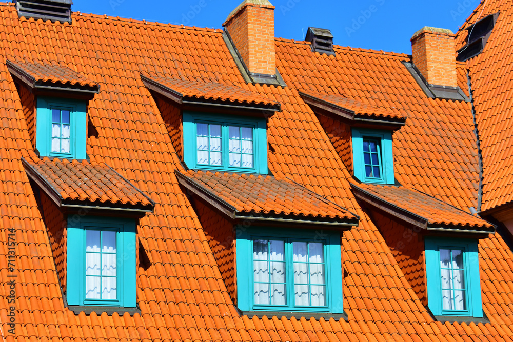 Red tiled roof of the old rustic building with turquoise shutters on the windows. Village. Poland, Torun, August 2023