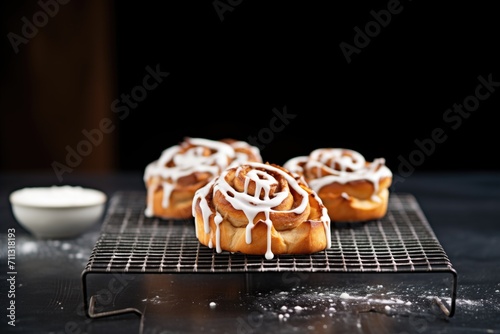 fresh cinnamon rolls with icing on a wire rack photo