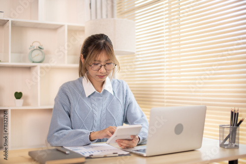 Woman working in front of laptop  Presses a calculator  Statistical graphs of investing in real estate  Finance  Accounting  Tex  Work for home.