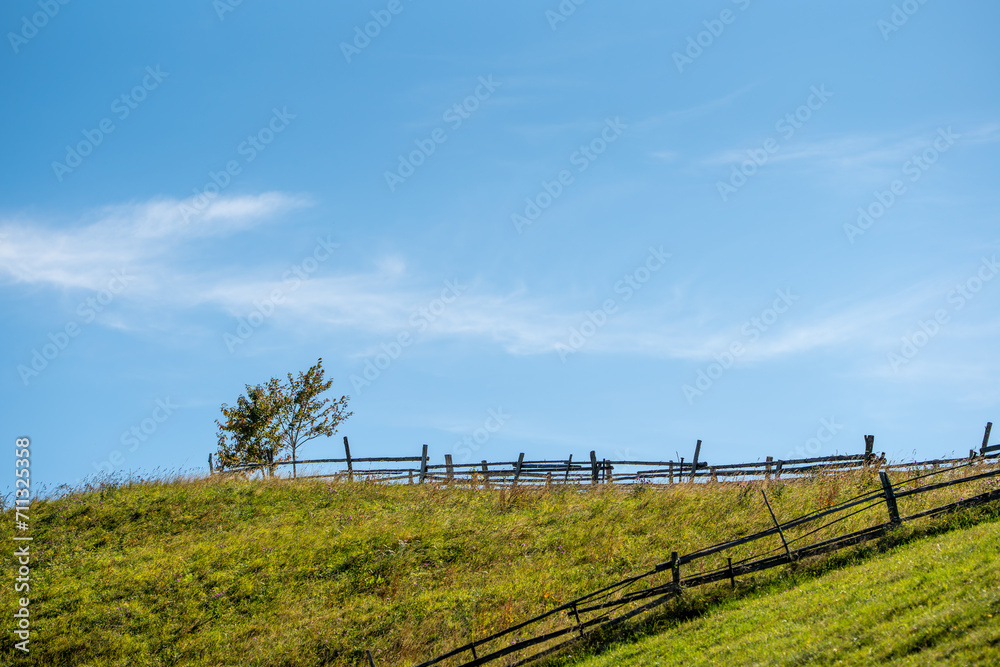Charming wooden fence atop a picturesque hillside, overlooking a peaceful meadow