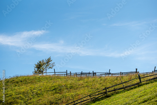 Charming wooden fence atop a picturesque hillside, overlooking a peaceful meadow