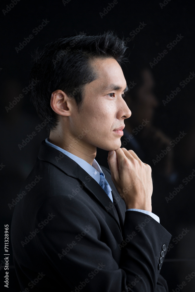 Chinese Business man leaning on a black wall Chinese Business man leaning on a black wall