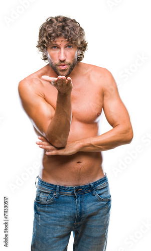 Handsome hispanic model man sexy and shirtless over isolated background looking at the camera blowing a kiss with hand on air being lovely and sexy. Love expression.