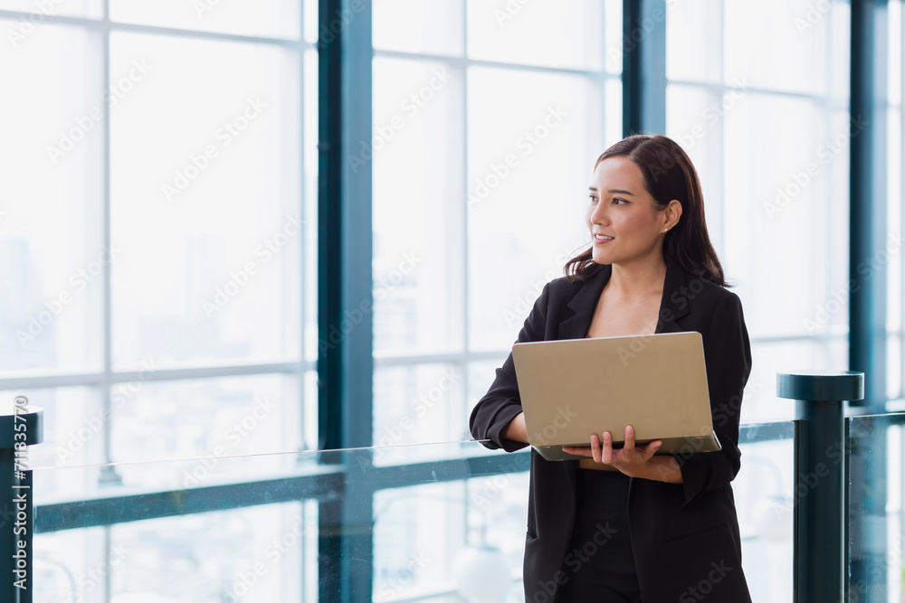 Businesswoman using laptop computer standing near workplace, touching. Young female office worker using apps at her laptop. Businesswoman using laptop computer standing near workplace, touching. Young female office worker using apps at her laptop.
