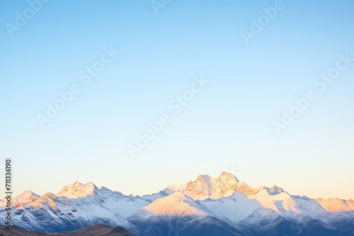 sunrise over snowcapped peaks with a clear blue sky