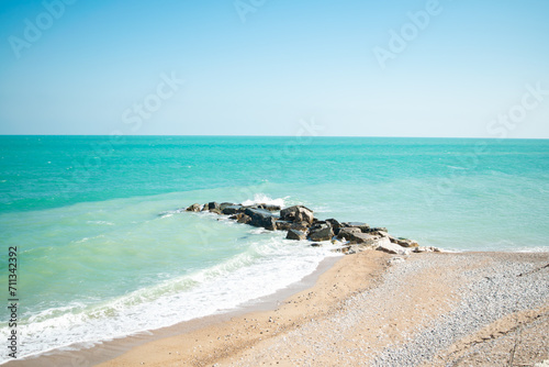 View of a turquoise water beach with a breakwater
