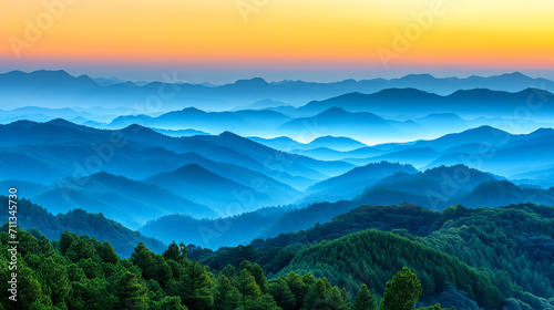 Dawn breaks over a peaceful forest with multiple layers of mountains fading into the distance under a soft orange sky