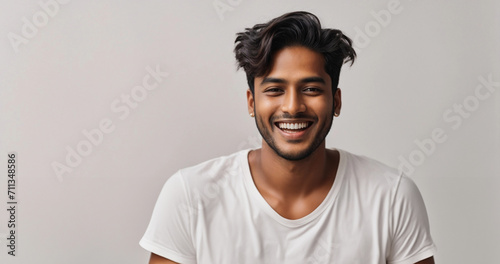 Happy young indian man with short hair laughing with pride and joy while holding a face product, his newest addition to his skincare
