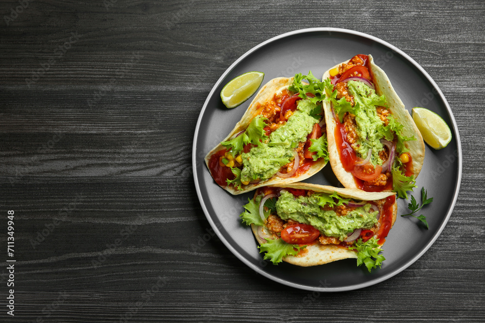Delicious tacos with guacamole, meat and vegetables on wooden table, top view. Space for text Delicious tacos with guacamole, meat and vegetables on wooden table, top view. Space for text