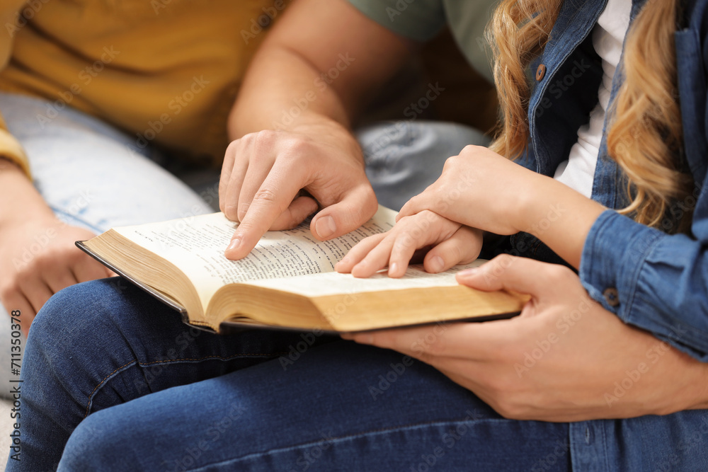 Girl and her godparents reading Bible together indoors, closeup Girl and her godparents reading Bible together indoors, closeup