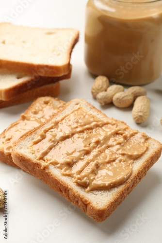 Delicious toasts with peanut butter and nuts on white table, closeup