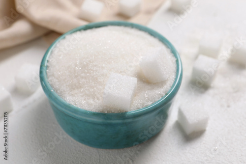 Different types of sugar in bowl on white table, closeup
