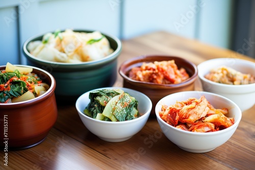kimchi varieties in ceramic bowls on a wooden table photo