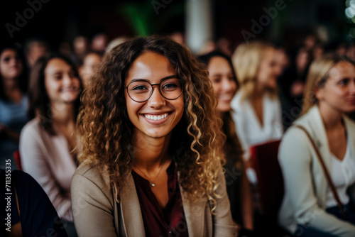 Smiling woman with curly hair and glasses at a social gathering, concept of happiness and community photo